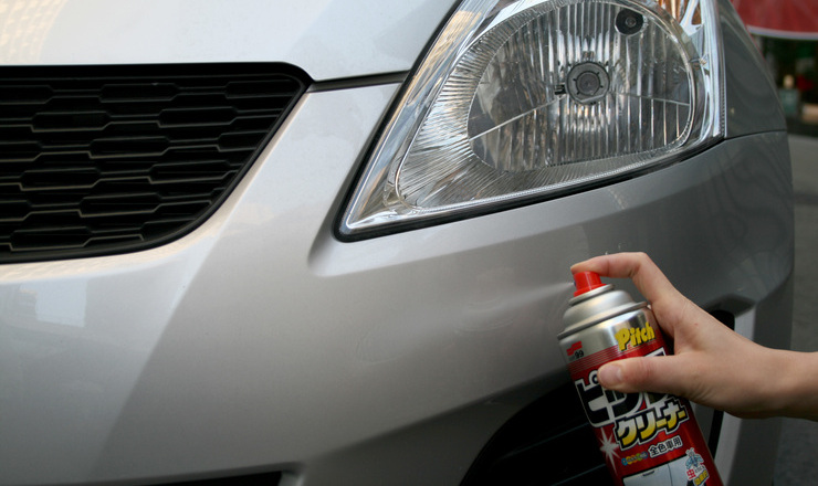 クリーナーを車に吹きかけている画像
